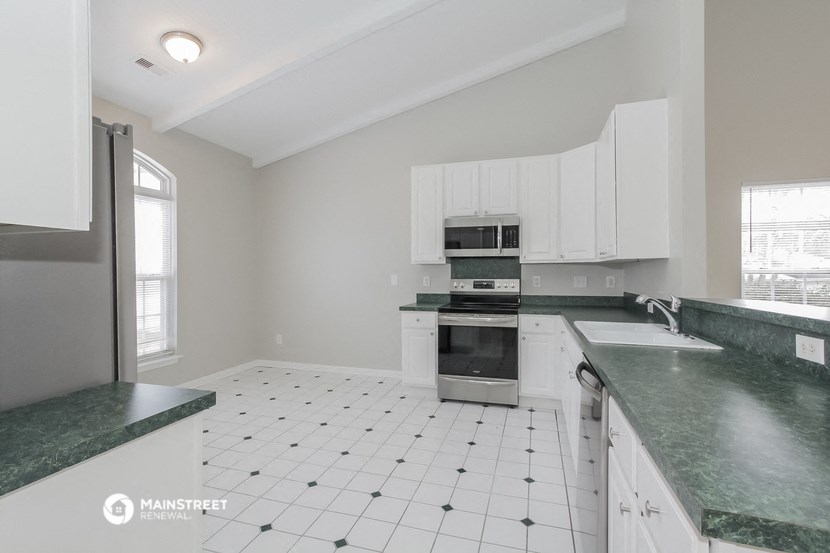 a kitchen with white cabinets and green counter tops and a stove and refrigerator