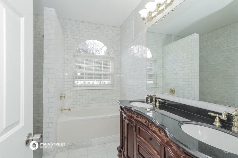 a bathroom with two sinks and a tub and a mirror