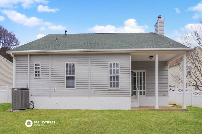 the front of a white house with a yard and a trash can