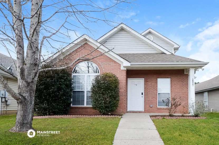 a brick house with a white door and a lawn