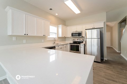 a white kitchen with stainless steel appliances and white counter tops