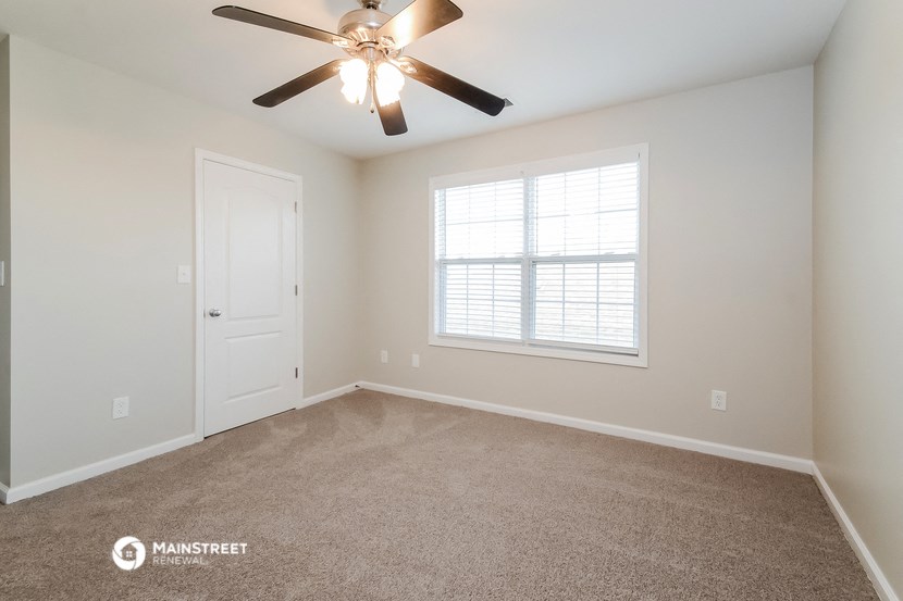 the spacious living room with ceiling fan and window