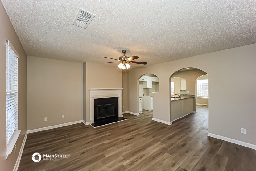 an empty living room with a fireplace and a ceiling fan