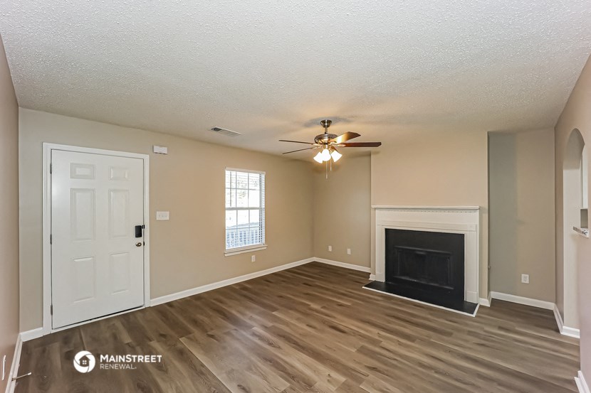an empty living room with a fireplace and a ceiling fan