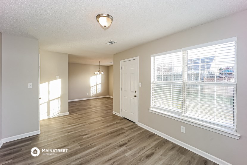 the living room and dining room of an apartment with wood flooring and large windows