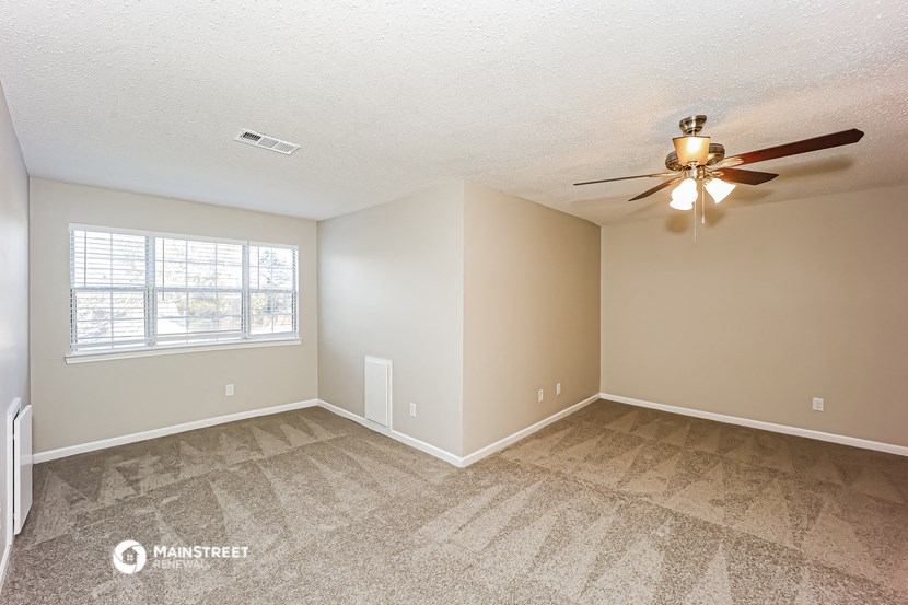 the spacious living room with carpet and a ceiling fan