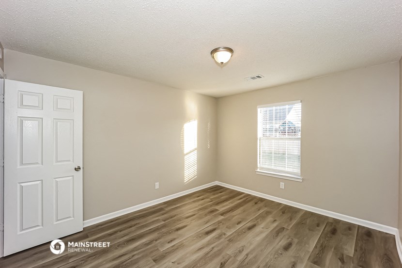 the spacious living room with wood flooring and a white door