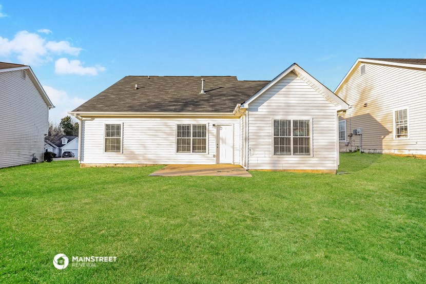 a backyard with a white house and a green lawn
