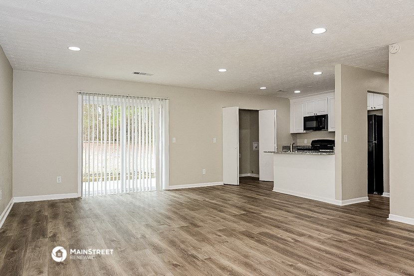 the living room and kitchen of an apartment with wood flooring