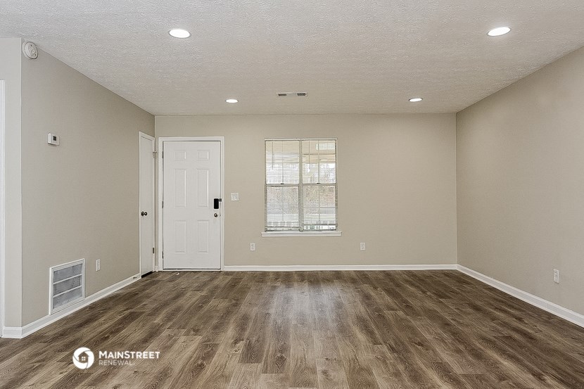 the spacious living room with hardwood flooring and a window