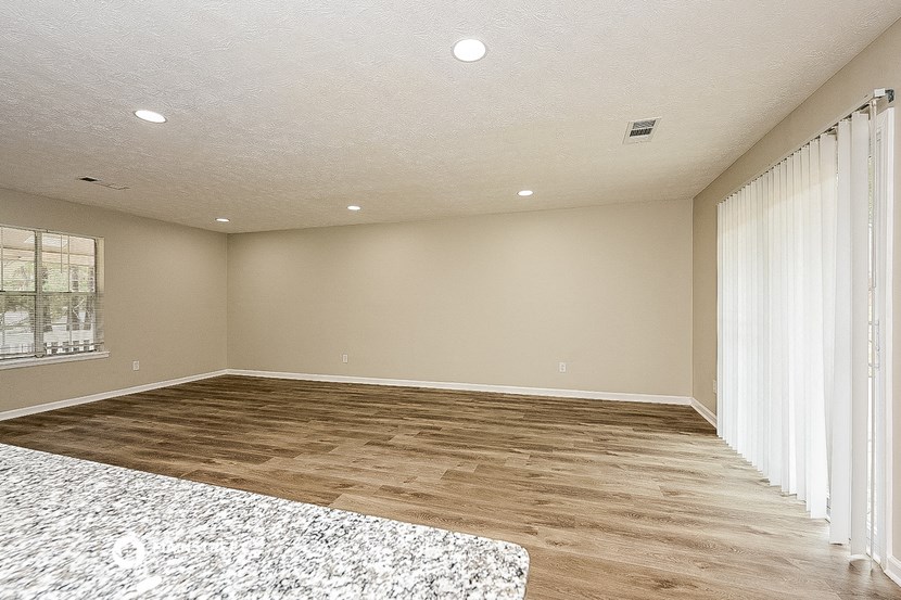 an empty living room with sliding glass doors to a patio