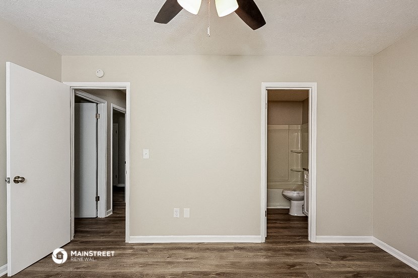 an empty room with a ceiling fan and a door to a bathroom