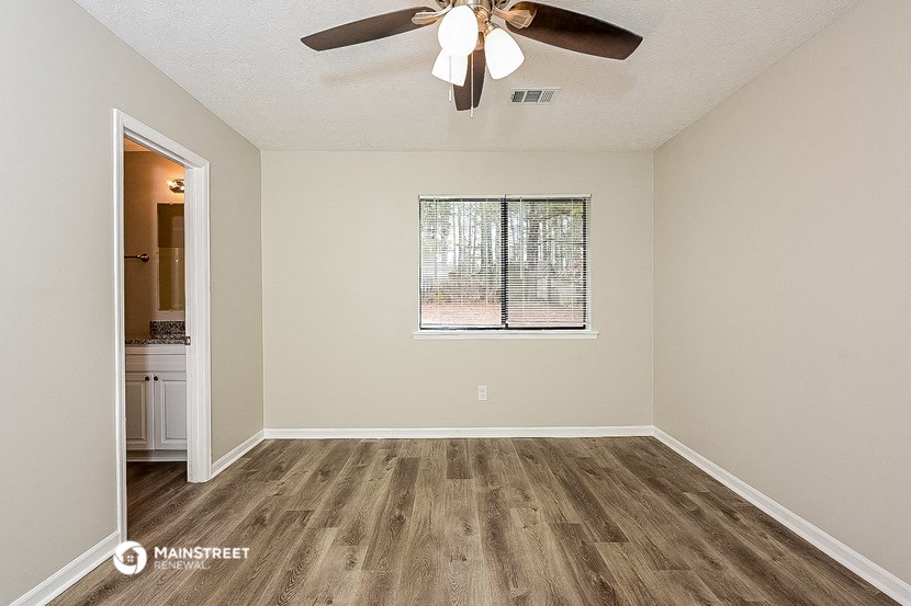 an empty living room with a ceiling fan and a window