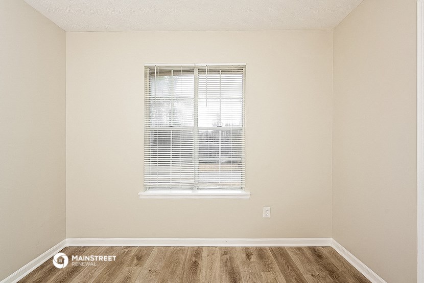 an empty room with a window and wooden floors