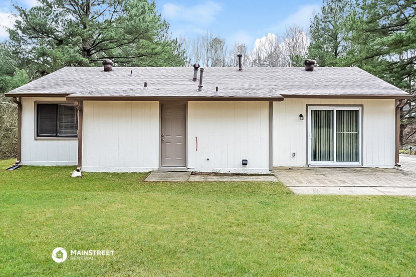 the front of a white house with a yard and trees