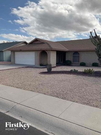 a house with a driveway and cactus in front of it