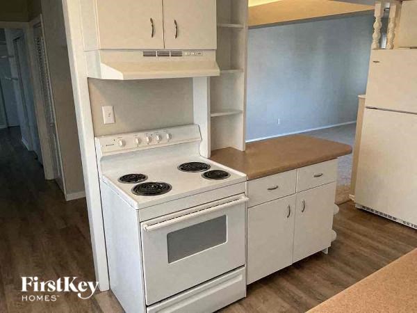 A white stove and oven in a kitchen with wooden floors.