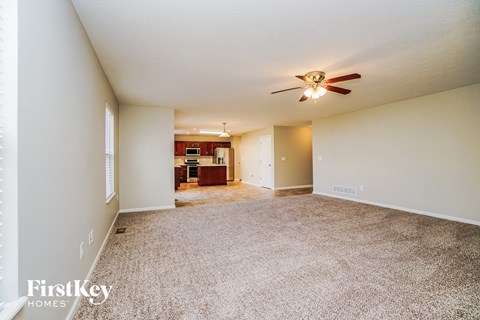 an empty living room with carpet and a ceiling fan