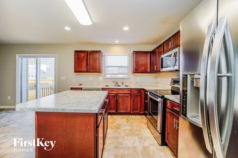 a kitchen with wooden cabinets and stainless steel appliances and a marble counter top