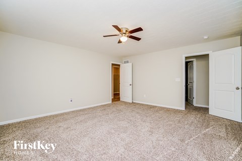 a spacious living room with carpet and a ceiling fan