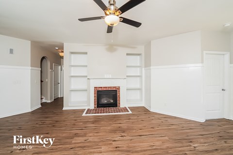 A living room with a fireplace and a ceiling fan.