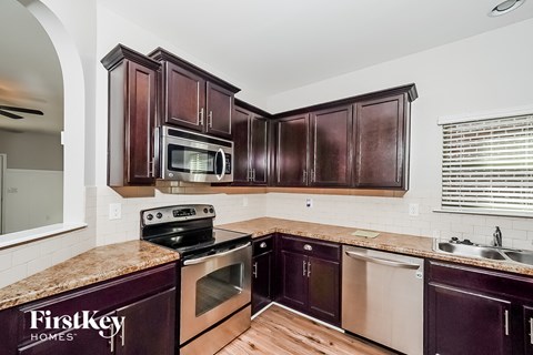 A kitchen with dark wood cabinets and a granite countertop.