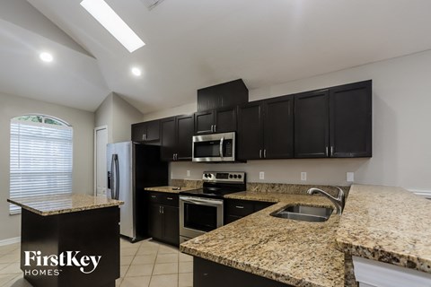 a kitchen with granite counter tops and black cabinets and stainless steel appliances