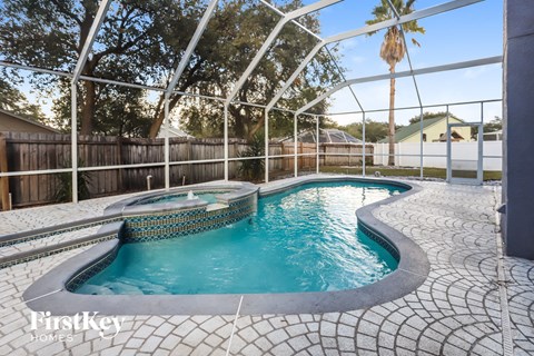 a pool and spa in a backyard with a fence and palm tree