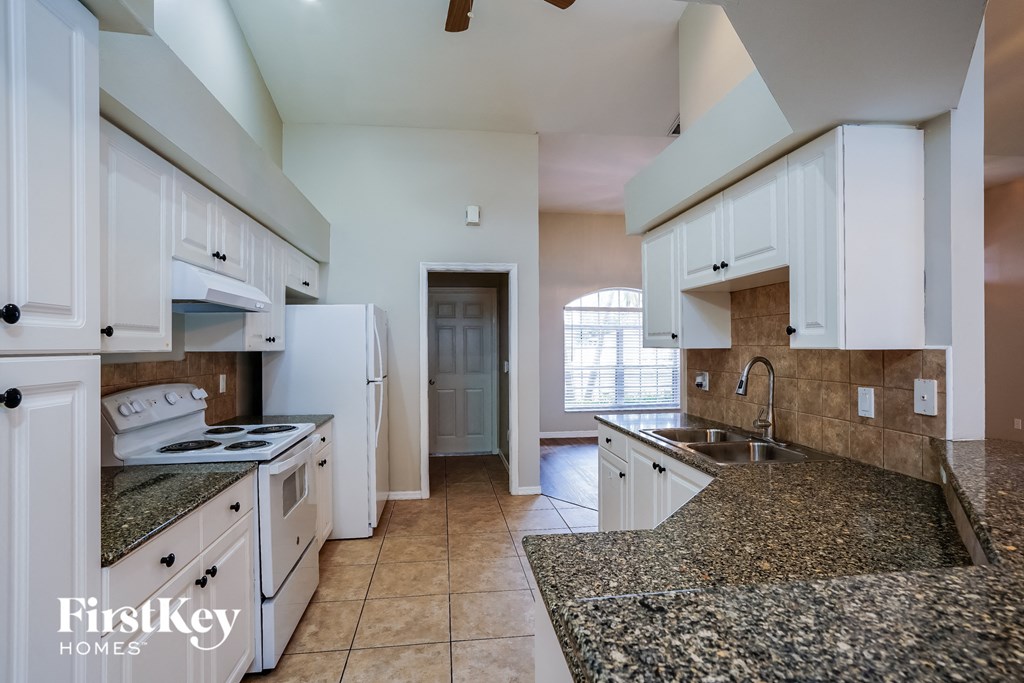 a kitchen with white cabinets and granite counter tops and a sink