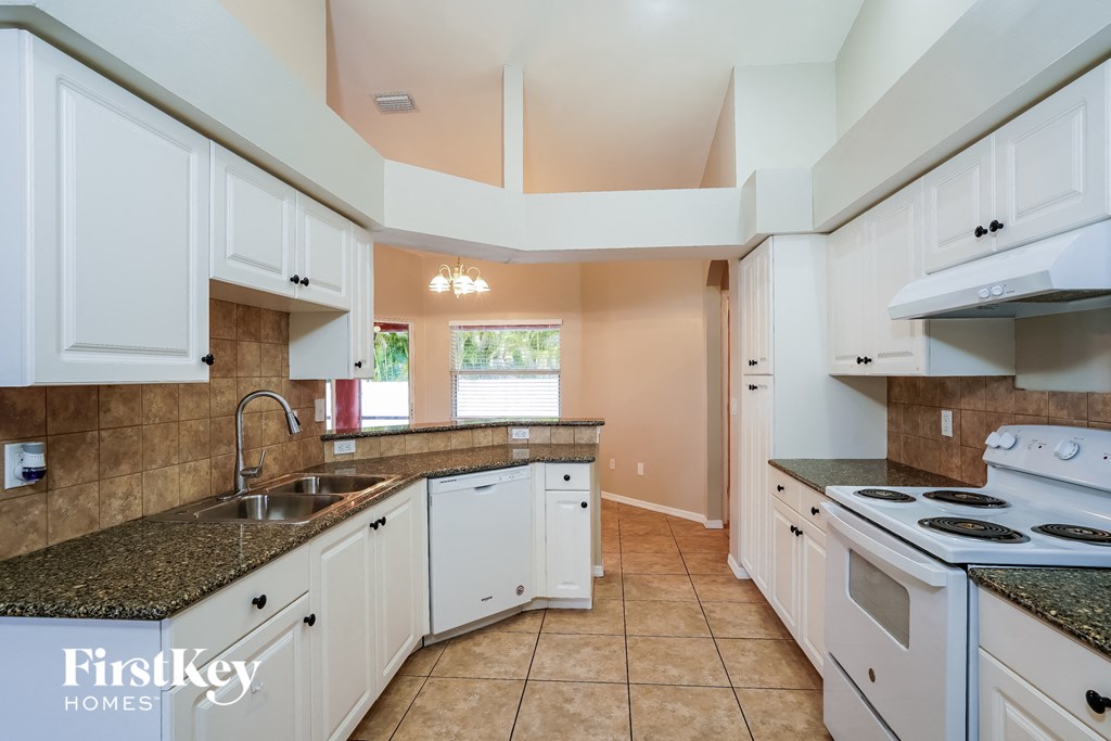 a kitchen with white cabinets and a sink and a stove