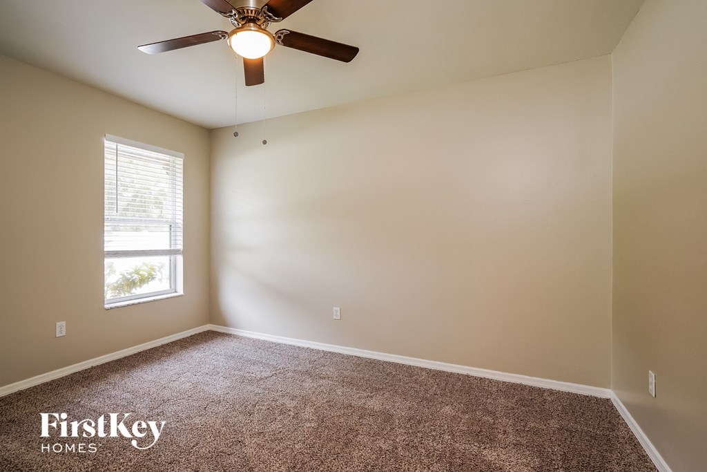 an empty room with a ceiling fan and a window