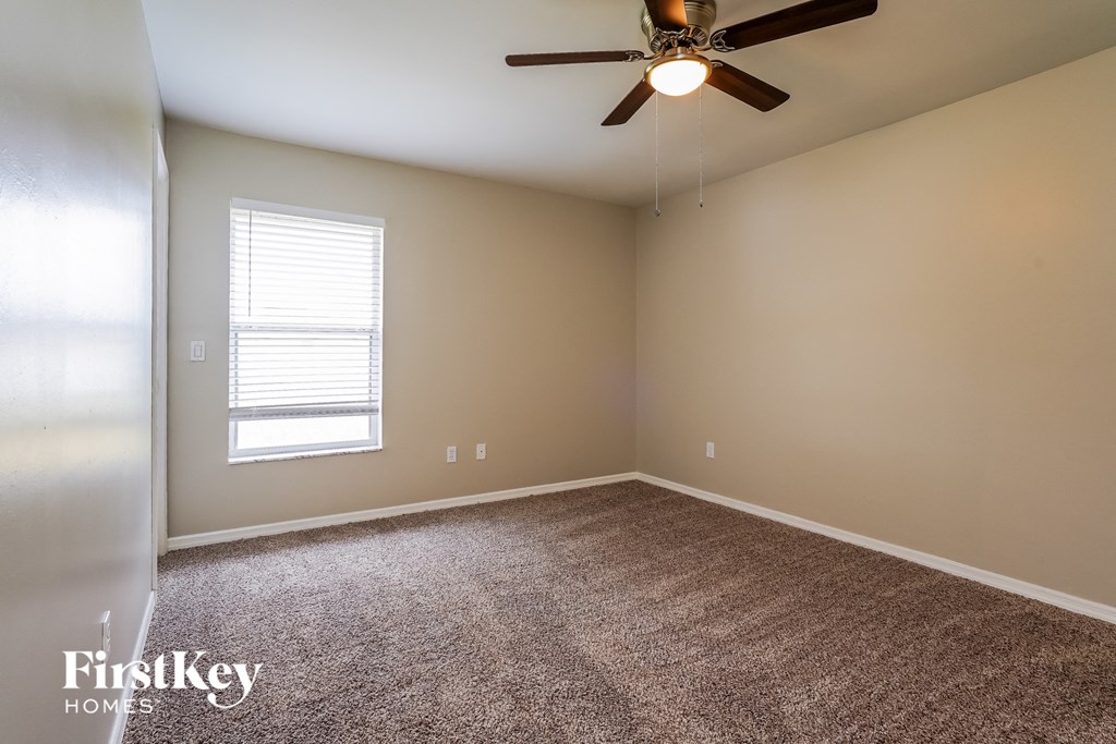an empty room with carpet and a ceiling fan