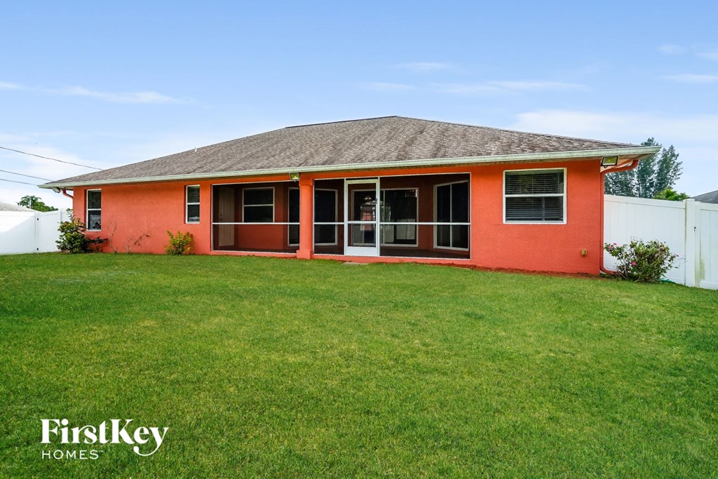 a red house with a grassy yard and a white fence