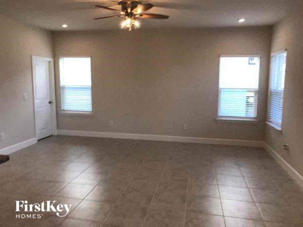 A room with a ceiling fan and two windows.