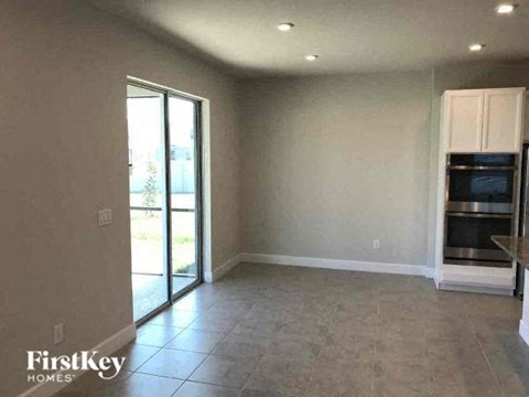 A spacious room with a kitchenette and a sliding glass door leading to a patio.