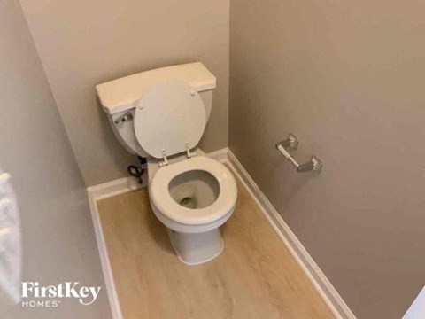 A white toilet in a small bathroom with wooden flooring.