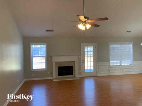 A spacious living room with a fireplace and a ceiling fan.