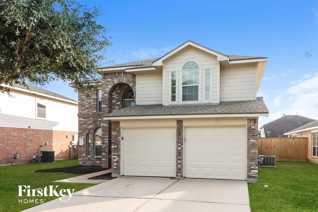 a home with a white garage door and a brick house