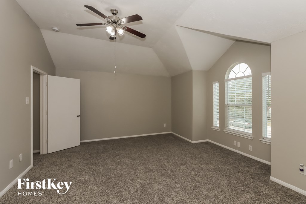an empty living room with a ceiling fan and windows