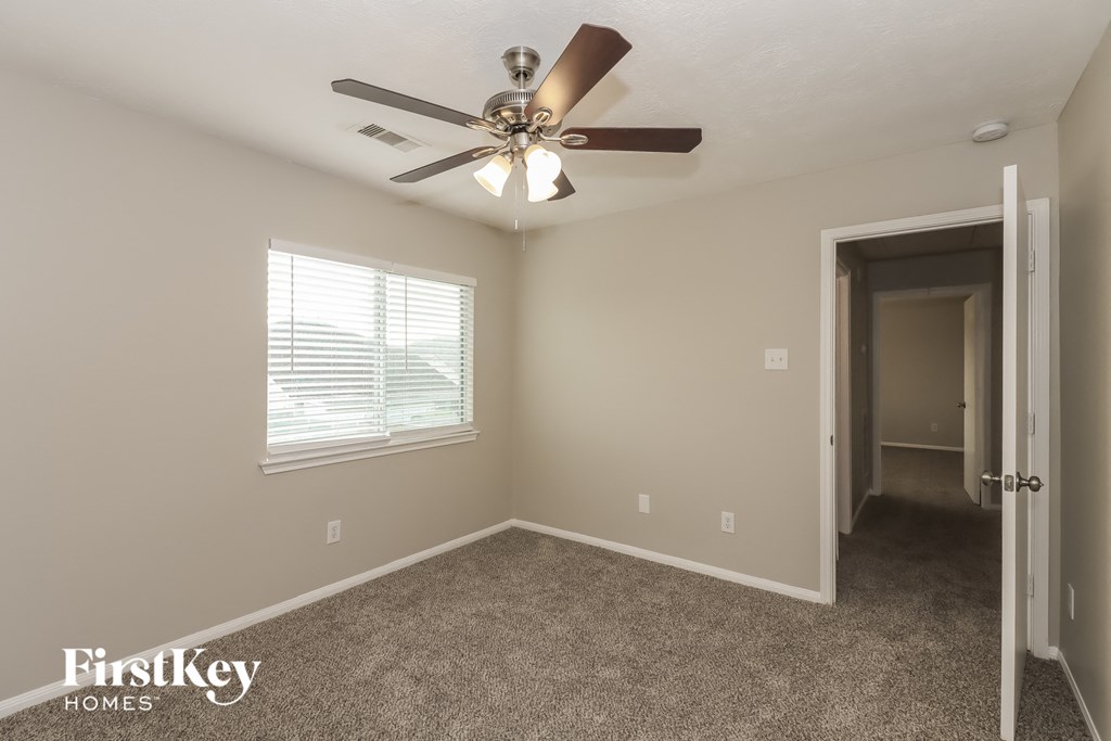 a bedroom with a ceiling fan and a door to a hallway