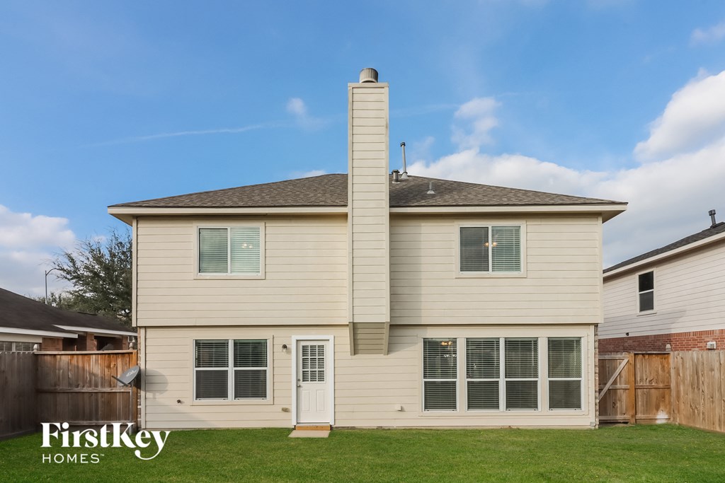 the back of a white house with a wood fence and a blue sky