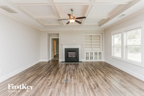 A spacious room with a fireplace and a ceiling fan.
