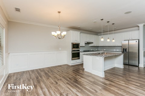 A well-lit kitchen with wooden floors and a marble island.