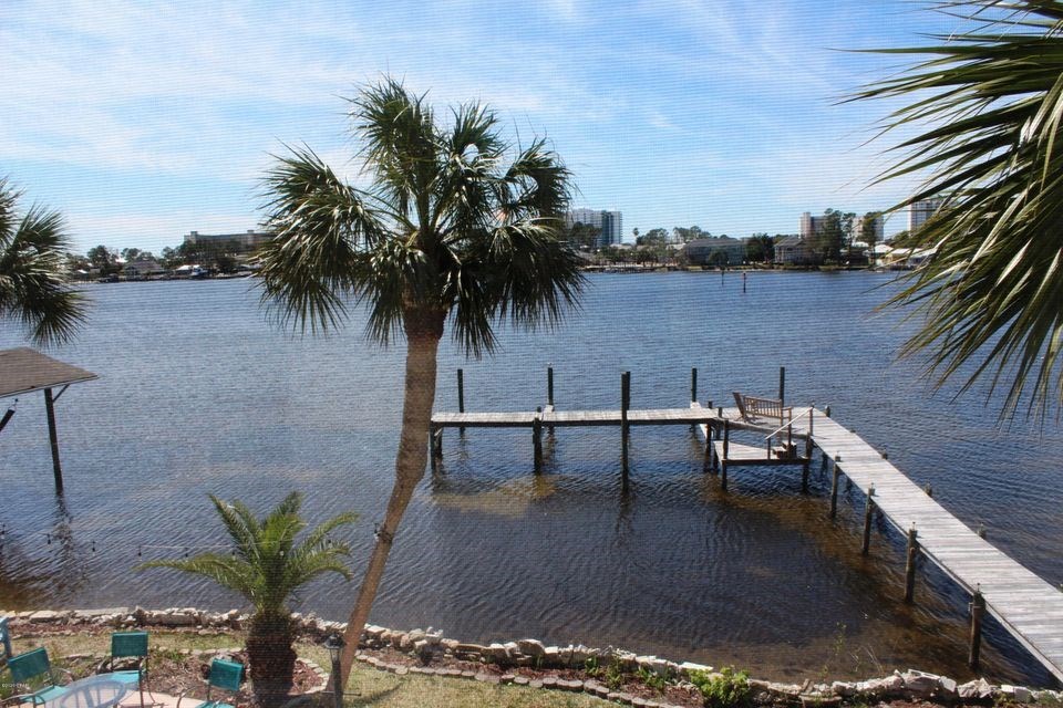 a dock on a body of water next to a palm tree