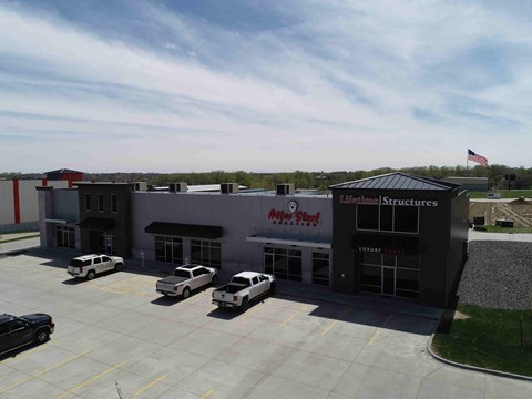 A building with a sign that reads "Mini-Tool" and "Structures" is surrounded by a parking lot with several cars.