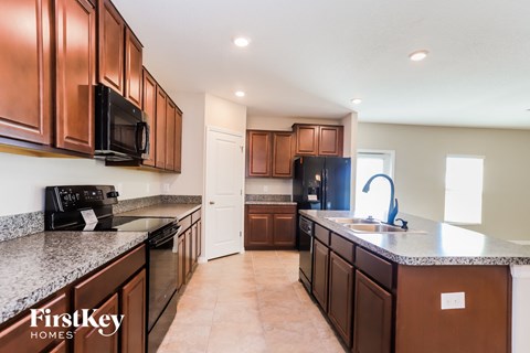 A kitchen with brown cabinets and a black microwave.