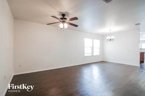 an empty living room with white walls and a ceiling fan