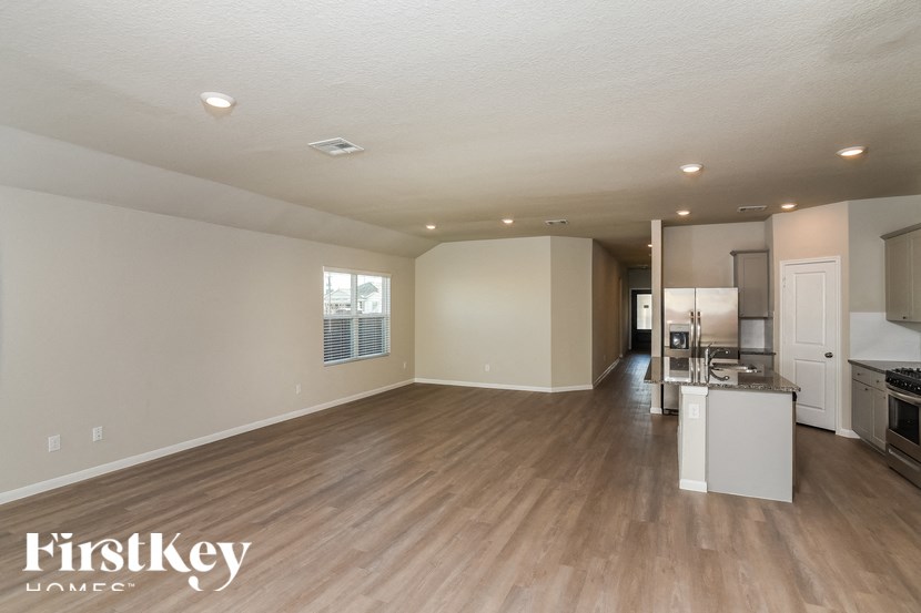 A spacious living room with a kitchen in the background.