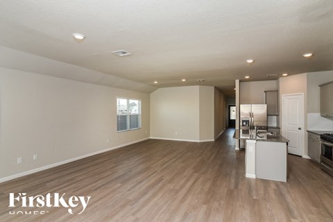 A spacious living room with a kitchen in the background.
