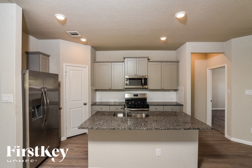 A kitchen with a granite countertop and stainless steel appliances.